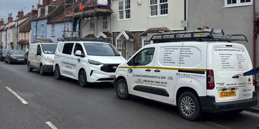 Three JD Home Improvements vans parked on a terraced street in Bristol, with scaffolding up on a house behind