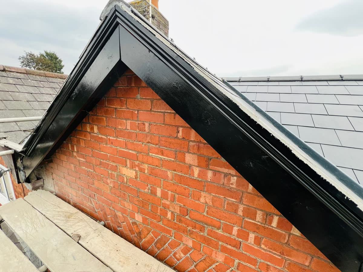 Black fascia along a gable with a slate roof behind in Staple Hill