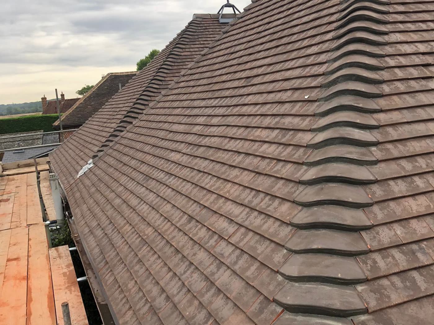 Same hip roof re-covered in new clay plain tiles with fresh bonnet hip tiles, Cotham